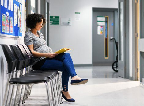 Expectant mother filling out paperwork at a hospital waiting room area