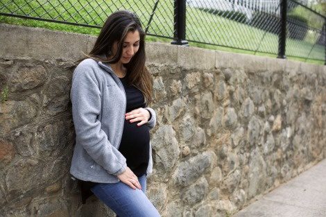 pregnant woman pauses to rest and looks down at her belly