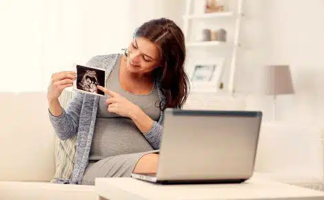 Happy woman shows her ultrasound photo during a Skype call