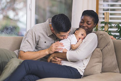 Happy adoptive family embrace their baby