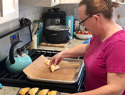 Kathryn puts peach hand pies onto a baking sheet