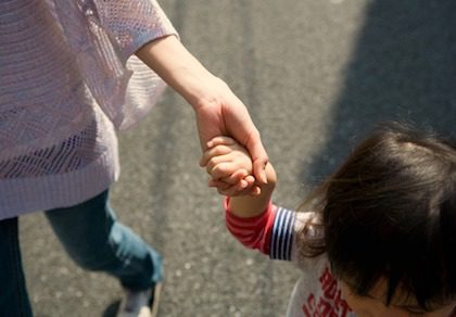 Adoptive mom holding her adopted child's hand while walking together
