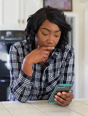 Pregnant woman looks at her phone in the kitchen