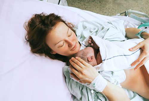 Young woman holding her baby immediately after delivery