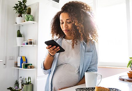 Pregnant woman in her kitchen looking at phone