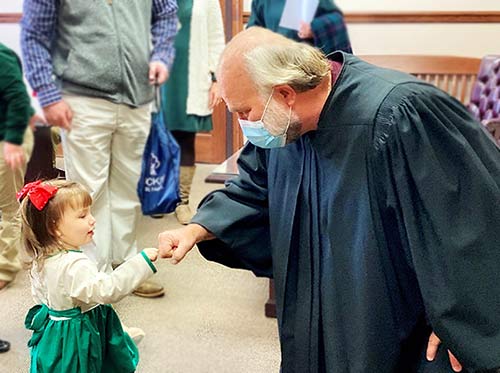 An adoptee and judge bump fists after her adoption is final
