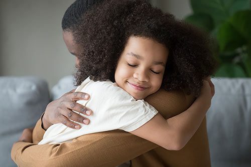 Grade-school aged girl hugs her father feeling love and connection