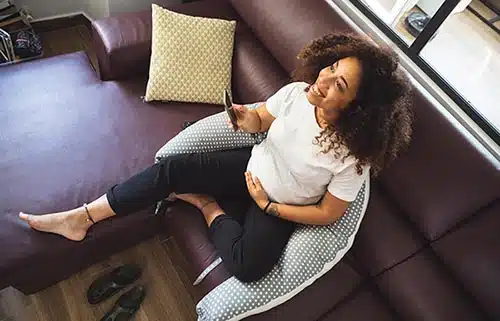 Happy pregnant woman with a pregnancy pillow, one of the best pregnancy hacks
