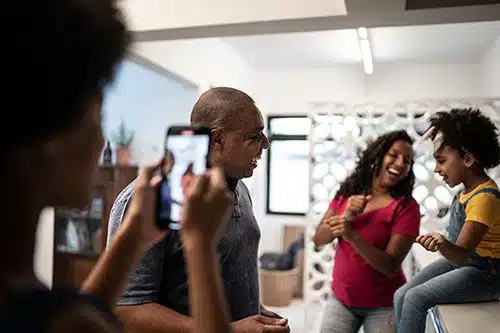 Adoptive family dancing in the kitchen while daughter films them