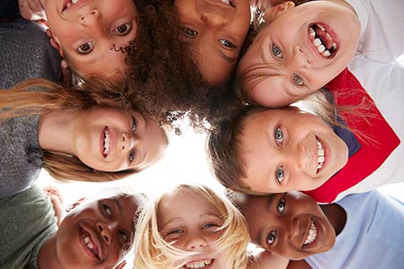 Group Of multi-cultural children with friends looking down into camera 