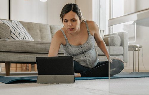 Pregnant woman taking an online childbirth class from her living room