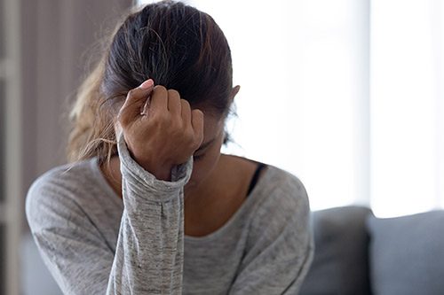 Young woman crying in her living room, experiencing postpartum depression after adoption