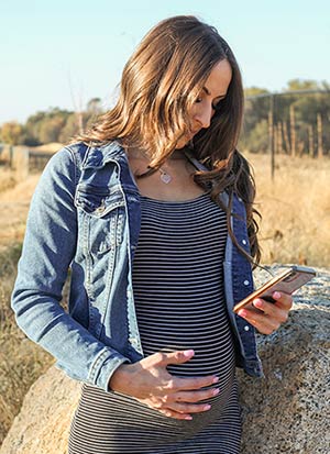 pregnant woman looking on her mobile phone for adoptive families