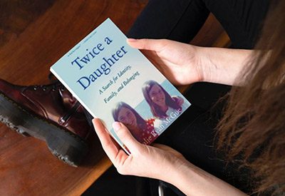 Person holding Julie McGue's book, "Twice a Daughter"