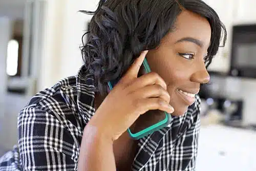 Young black woman having a phone conversation in her kitchen