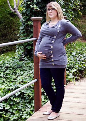 Pregnant woman deep in thought, on a small bridge at a park
