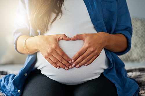 Closeup shot of an unrecognizable pregnant woman making a heart shape with her hands on her belly