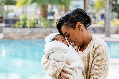 African American woman embraces infant son, whom she adopted after following Florida adoption laws
