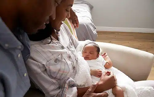 Adoptive parents gaze at their newborn baby