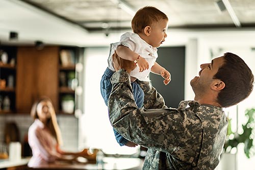 Happy military officer having fun with his infant son at home