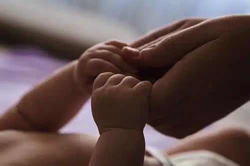 Mother holds her infant daughter's hands
