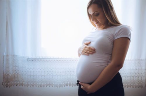 Pregnant woman holding her belly as she thinks about adoption compensation for birth mother