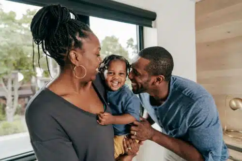 Happy adoptive couple share a giggle with their toddler son
