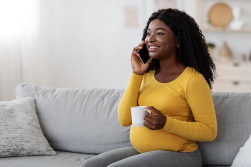 pregnant young woman drinking tea and talking on phone