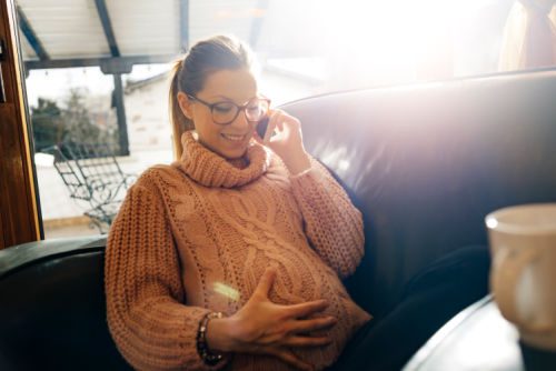 Cheerful pregnant woman talking on her smartphone to a potential adoptive parent