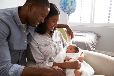 Adoptive parents smile down at their newborn child