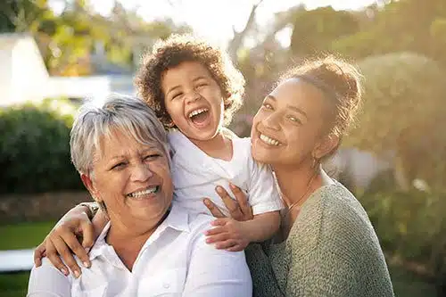 Adoptive mother, adoptee, & birth mother pose for a photo happy in their successful open adoption