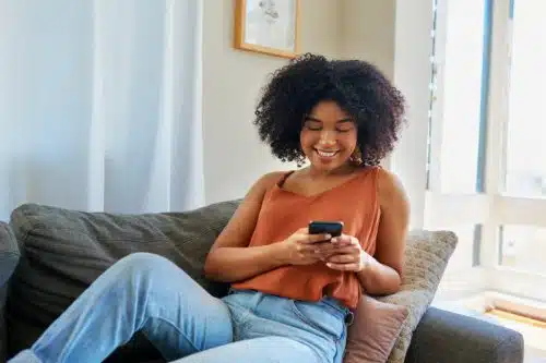 A young woman who was adopted scrolls through adoptee's stories on Tik Tok in her living room