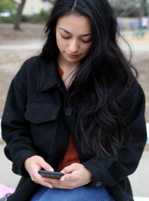 Young woman at the park texting with a friend
