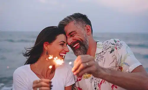 An adoptive couple having fun with sparklers on the beach during a vacation
