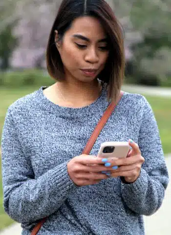 Pregnant woman outside looking at a pregnancy app on her iPhone