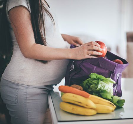 pregnant woman unpacking healthy fruits