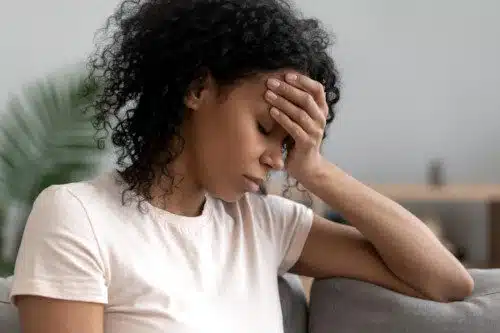 African American woman sitting on couch feeling unhappy 