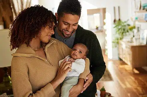 Smiling parents cradling their cute little baby boy in their arms 