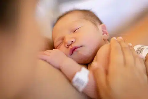 A mom holds her newborn baby at the hospital while thinking abut safe haven or a baby box