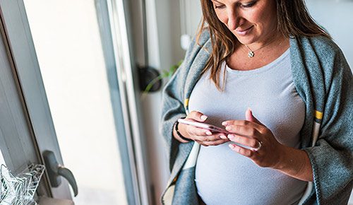 Pregnant woman looking up private adoptions on her phone