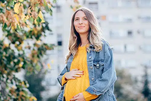 Pregnant woman in a park holding her belly