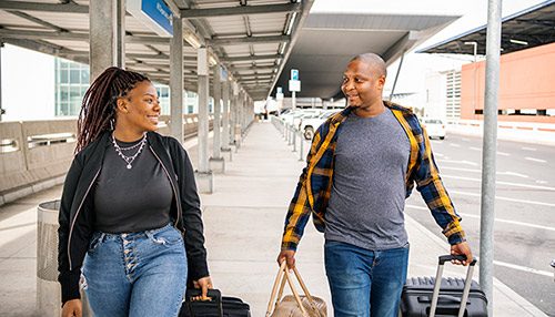 Smiling couple walking with baggage outside an airport terminal