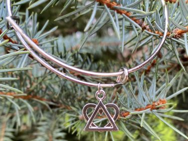 An adoption bracelet in the bangle style featuring an adoption symbol charm