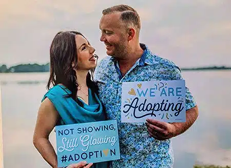 Lifetime adoptive couple Liesa and Brant proudly hold their adoption signs
