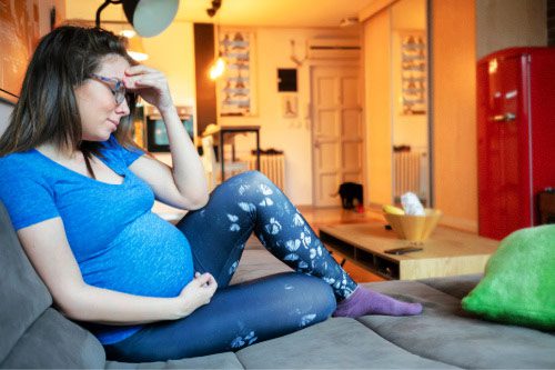 Expectant woman stressed at home about whether adoption is a good choice