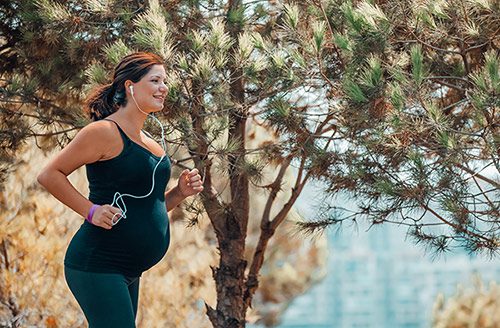 Smiling pregnant woman on a walk in nature, one of the best pregnancy-safe workouts
