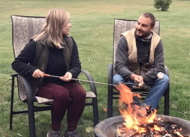 Jess and Ryan roasting marshmallows on a campfire and chatting