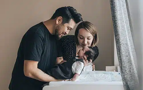 Young couple admiring their newborn baby after changing his diaper