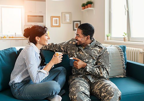 A member of military and his wife in their living room talking about adopting