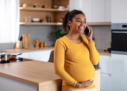 Young pregnant women in her kitchen on the phone
